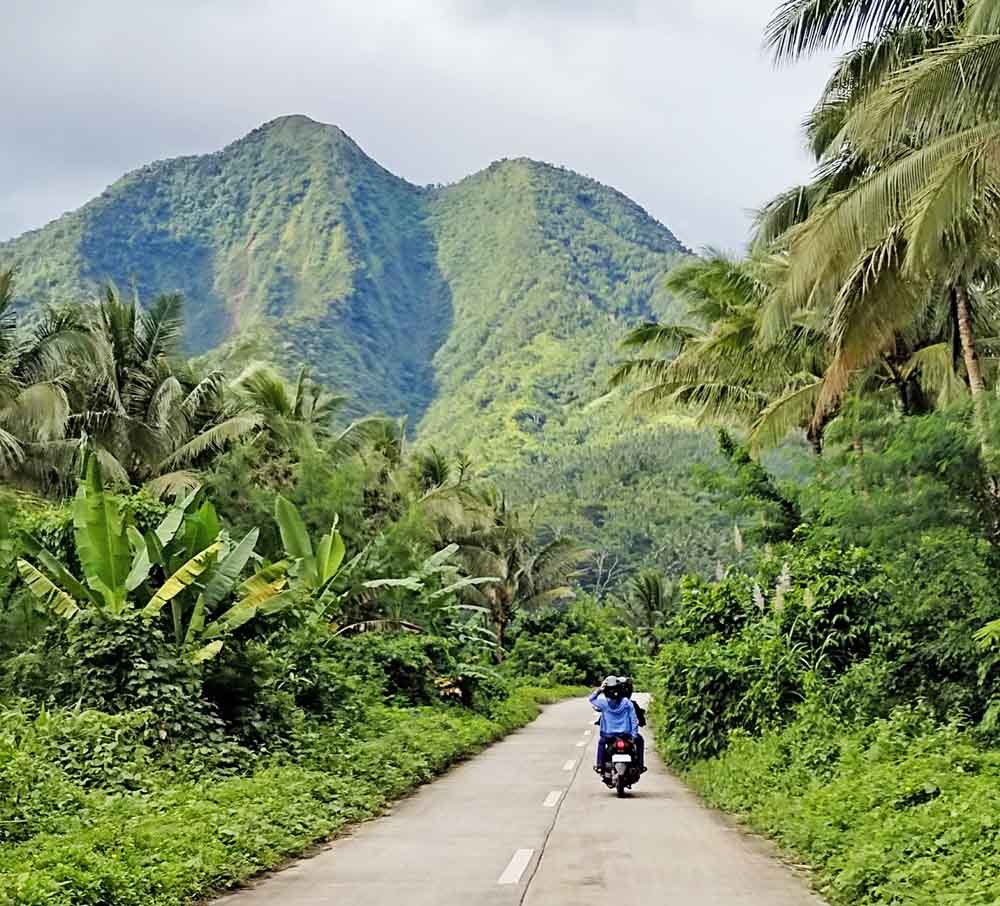 A motorcycle following along the highway with a view of the mountains up ahead.