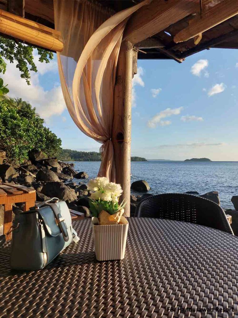 A bag on top of the table facing the view of the blue oceans.