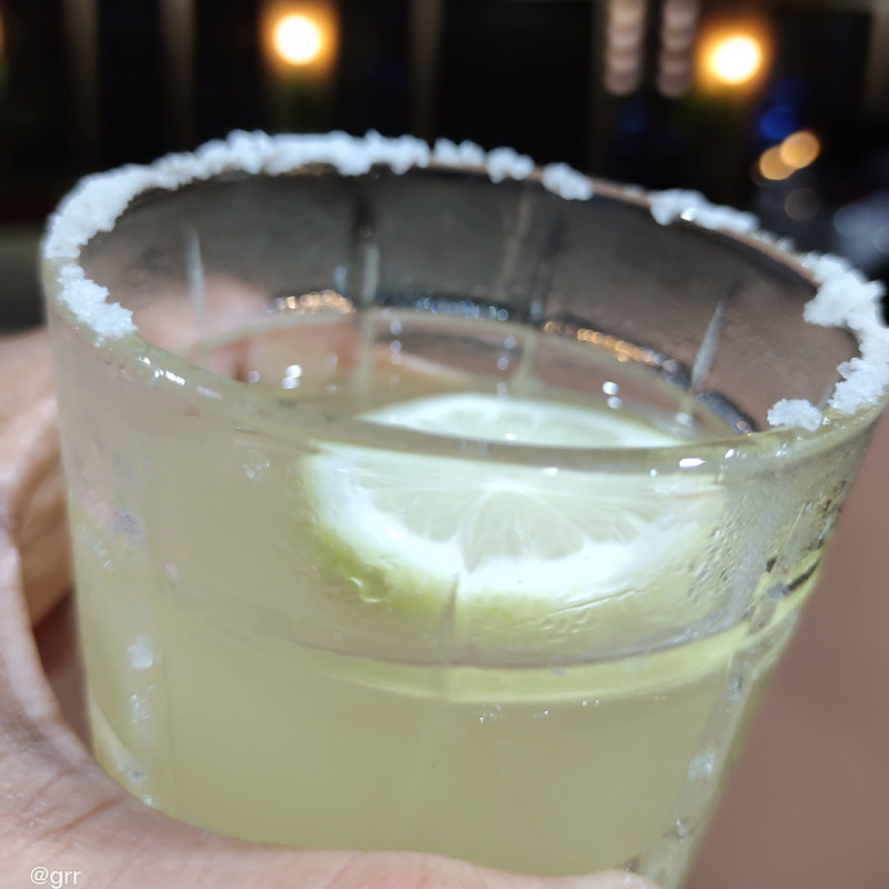 Holding a margarita drink at night time.