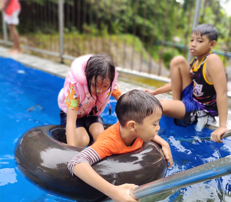 Kids in the pool riding a donut floater.