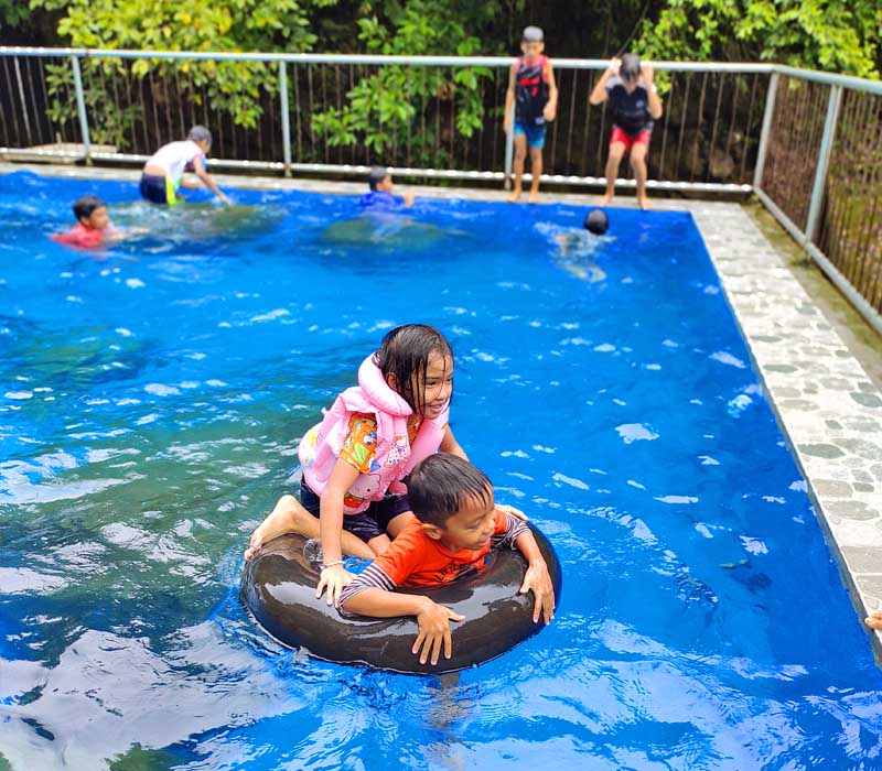 Kids in the swimming pool enjoying the ride in the donut floater.